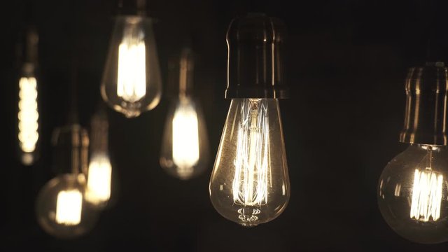 Vintage style light bulbs swinging on the wire in the house. Decorative lights at home. Old Edison bulb.