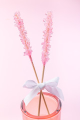 Rock candy on pink paper background decorated with a white bow, vertical