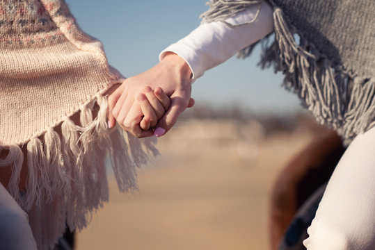 mother and daughter hold each other's hands while riding on the seashore