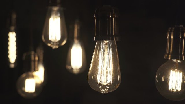 Vintage style light bulbs swinging on the wire in the house. Decorative lights at home. Old Edison bulb.