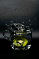 Fresh fruit falling into a glass filled with water.