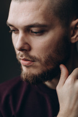 Obraz premium close-up portrait of a serious young man looking away on a gray background. bald with a beard