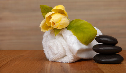 Roll of white towels on table, yellow flower -  with copy space.