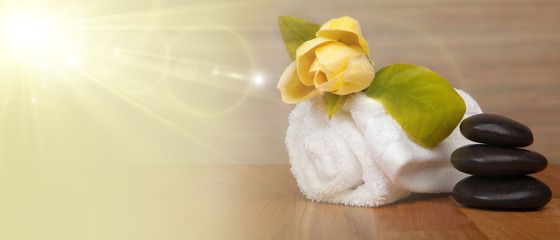Beauty treatment and wellness background with massage pebbles, magnolia flower, towels.