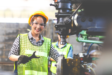 Woman worker wearing safety goggles control lathe machine to drill components. Metal lathe industrial manufacturing factory