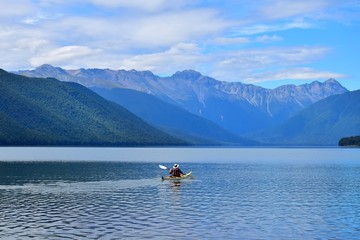 A man paddling across Lake Rotoroa in the Nelson Lakes National Park, New Zealand, South Island.