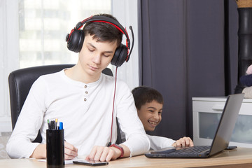 teenager looks at a laptop and writes down a task and children interfere with learning