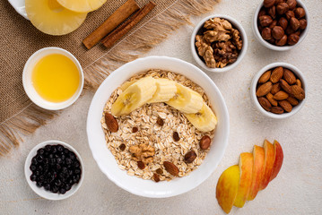 Breakfast oatmeal with fruits, nuts, banana, honey, apple. Healthy breakfast cereal. Top view.