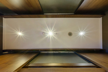 look up on suspended ceiling with halogen spots lamps and drywall construction with fire alarm...