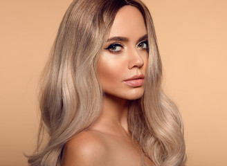 Ombre blond wavy hairstyle. Beauty fashion blonde woman portrait. Beautiful girl model with makeup, long healthy hair style posing isolated on studio beige background. - obrazy, fototapety, plakaty