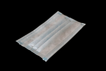 Side view of light blue disposable medical face mask isolated on black background.