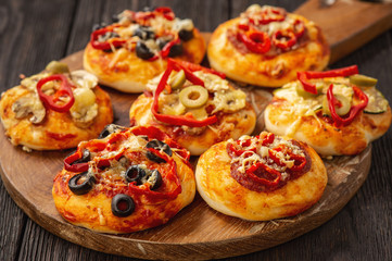 Homemade mini pizza with salami, pepper, olives and cheese.