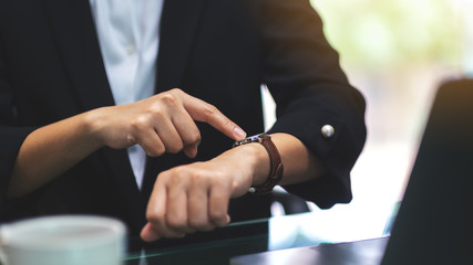 A business woman pointing at a wristwatch on her working time while waiting for someone in office