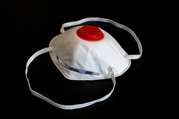 White N95 respirator face mask with red filter isolated on black background, rubber bands spread out