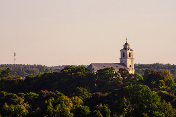 A white big church on a hill between trees
