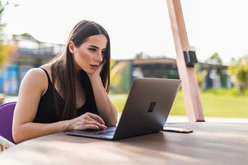 Beautiful young girl with a laptop working in beach cafe