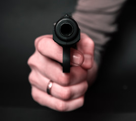 Male hand with gun isolated on black background. Man with a gun ready to shoot, focus on the weapon.