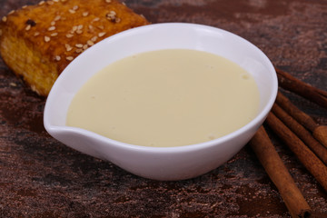 Condenced milk in the bowl with sinnamon and pastry