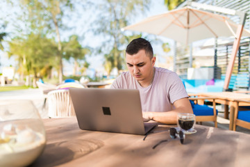 Young handsome businessman working with laptop in cafe outdoors