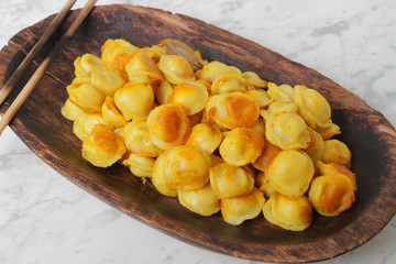 
fried ravioli in olive oil and served in a wooden plate on a marble table.