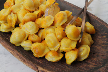
fried ravioli in olive oil and served in a wooden plate on a marble table.