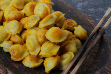 
fried ravioli in olive oil and served in a wooden plate on a marble table.