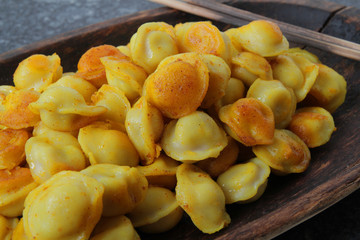 
fried ravioli in olive oil and served in a wooden plate on a marble table.