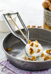 A ball of soft creamy vanilla icecream wiht nuts on delicate background