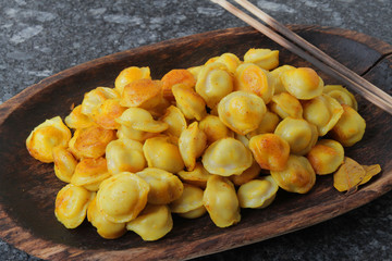 
fried ravioli in olive oil and served in a wooden plate on a marble table.