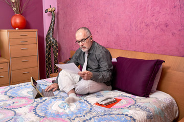 Fototapeta premium Businessman working from home with laptop, wearing shirt and tie and pajamas