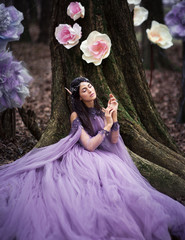 Fototapeta premium elf proncess in violet dress among flowers in forest