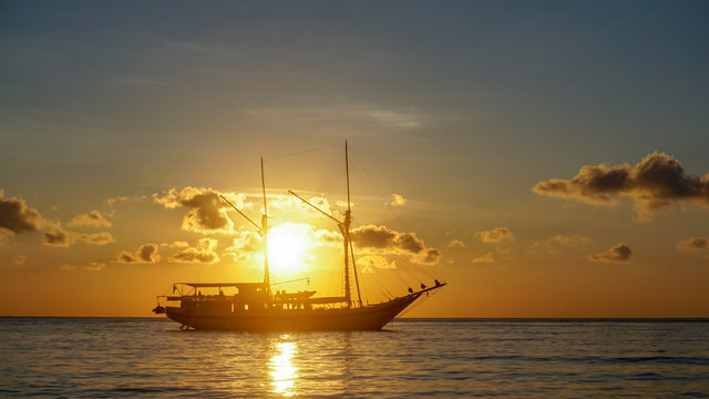 Indonesien, Bali, Kabupaten Karangasem, Sonnenuntergang auf dem Meer mit einem einsamen Schiff im Hintergrund
