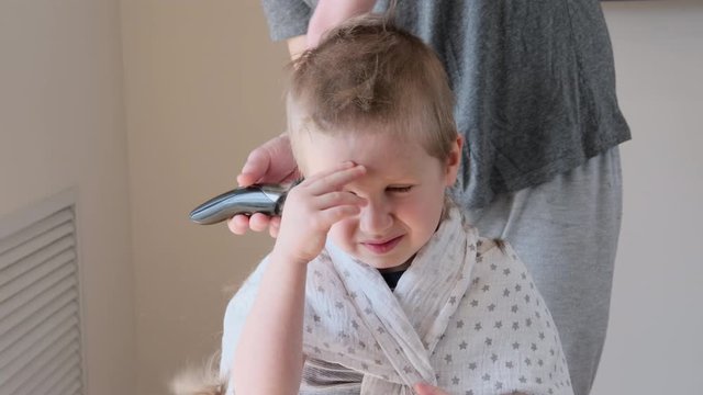 Self-isolation concept. Father cutting the hair of a little son with a hair clipper at home during the coronavirus quarantine. Self-isolation concept