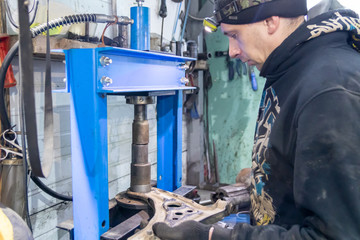 car mechanic installing silent blocks on the press