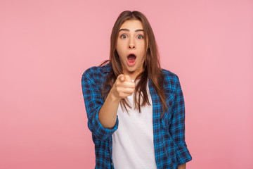 Wow, hey you! Portrait of astonished girl in checkered shirt pointing to camera, standing with surprised shocked expression on face, hard to believe. indoor studio shot isolated on pink background