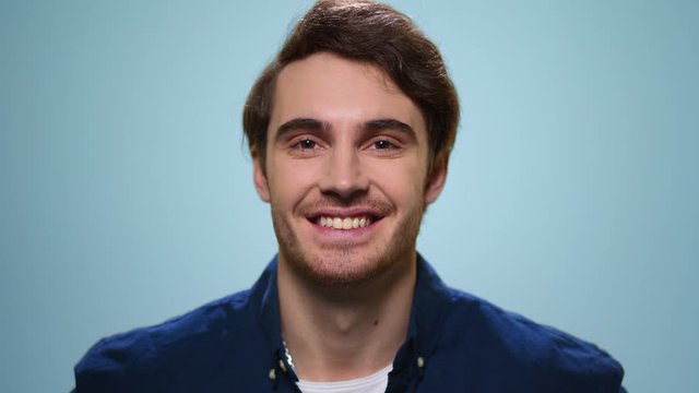 Handsome man smiling on blue background. Smiling guy standing in studio