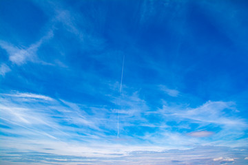 Horizontal view of a light, blue sky with white clouds. Airy, vibrant atmosphere