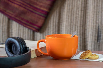Cozy still life with an orange mug, headphones and a book