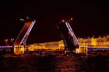 Fototapeta na wymiar Open bridge over the river in the evening city. Drawbridge in Saint Petersburg with night lights