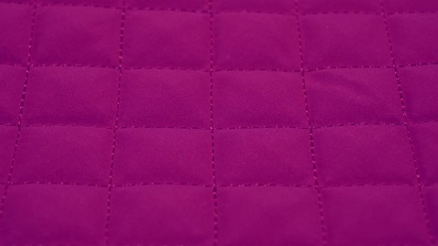 Closeup view video of bright pink quilted texture of fabric.