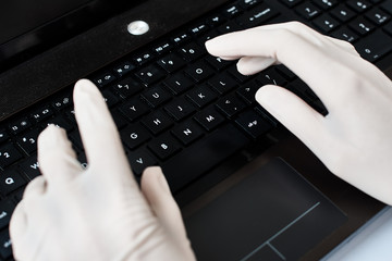 Hands in gloves typing on the laptop keyboard. Virus protection concept