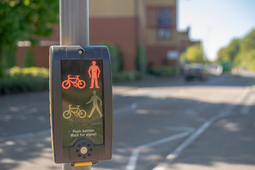 Close up of Traffic Light buttons with blurred cars in the background on a bright sunny day