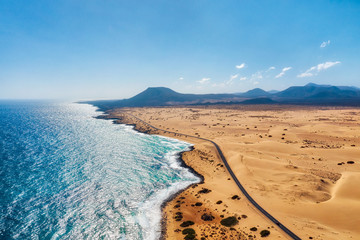 Rocky coastline and highway with golden sand and blue water
