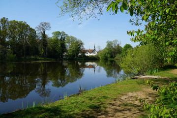 Fototapeta na wymiar House next to pond in Hampshire UK with nice green and blue colours and reflective water