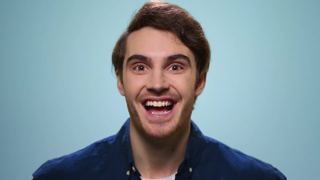 Surprised man posing on blue background. Excited guy looking at camera