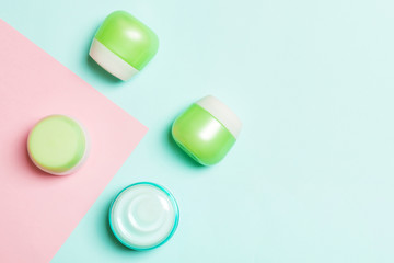 Top view of cosmetic containers, sprays, jars and bottles on pink background. Close-up view with empty space for your design