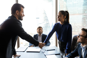 Smiling friendly businesswoman hr manager greeting candidate at meeting, shaking hand, congratulating successful applicant with getting job, business partners handshaking, celebrating deal