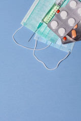 Medical masks with pills and syringe on a blue background. Copy space