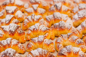 Croissants made in an artisanal way, freshly baked with its characteristic golden color, with powdered sugar on its surface, selective focus
