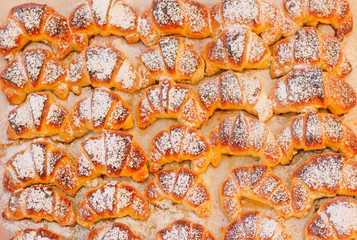 Croissants made in an artisanal way, freshly baked with its characteristic golden color, with powdered sugar on its surface, selective focus